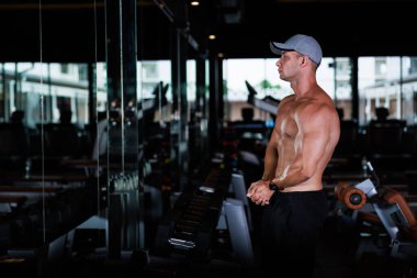 portrait foreigner trainer man poses showing his muscles in gym,