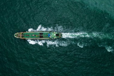 Aerial top view Oil ship tanker sailing full speed with wave and splash water in line of transportation from refinery in green sea. business and industry vesels service concept from drone camera 