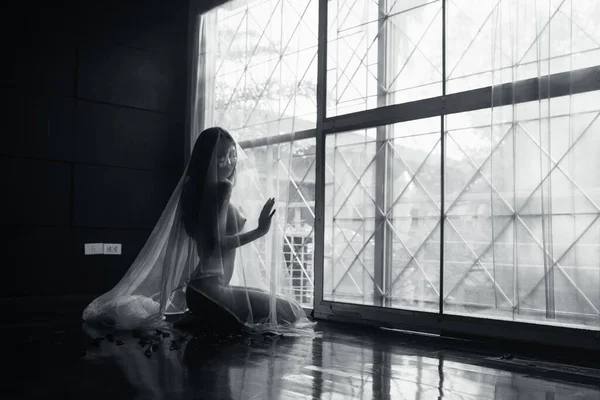black and white young asian women model sitting poses naked by the window light only a thin curtain envelops her and dark background, lady sexy emotion of art concept,