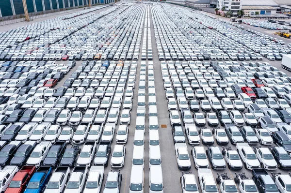 Rows of a new cars automotive line up products parked in warehouse of  factory for distribution dealers trading in import export, aerial view
