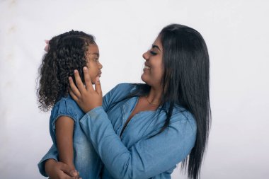 Fotoğraf stüdyosunda beyaz arka planda kızı olan genç bir anne.