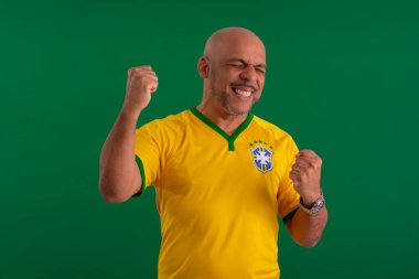 2022 kupasında Brezilya futbol takımını destekleyen Afro Brezilyalı bir adam, Brezilya bayrağı ve yüz ifadeleriyle.