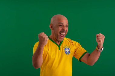 2022 kupasında Brezilya futbol takımını destekleyen Afro Brezilyalı bir adam, Brezilya bayrağı ve yüz ifadeleriyle.