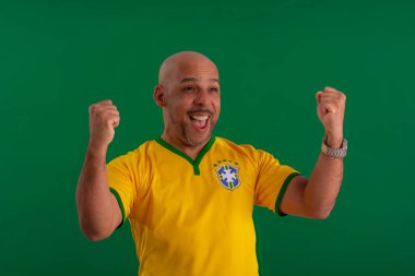 2022 kupasında Brezilya futbol takımını destekleyen Afro Brezilyalı bir adam, Brezilya bayrağı ve yüz ifadeleriyle.