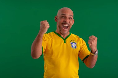 2022 kupasında Brezilya futbol takımını destekleyen Afro Brezilyalı bir adam, Brezilya bayrağı ve yüz ifadeleriyle.