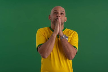 2022 kupasında Brezilya futbol takımını destekleyen Afro Brezilyalı bir adam, Brezilya bayrağı ve yüz ifadeleriyle.