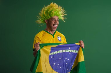 2022 kupasında Brezilya futbol takımını destekleyen Afro Brezilyalı bir adam, Brezilya bayrağı ve yüz ifadeleriyle.