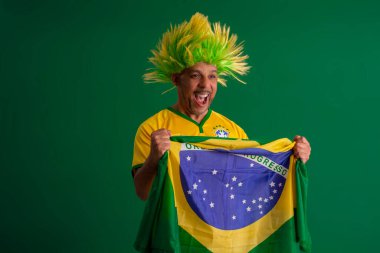 2022 kupasında Brezilya futbol takımını destekleyen Afro Brezilyalı bir adam, Brezilya bayrağı ve yüz ifadeleriyle.
