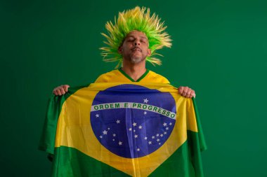 2022 kupasında Brezilya futbol takımını destekleyen Afro Brezilyalı bir adam, Brezilya bayrağı ve yüz ifadeleriyle.