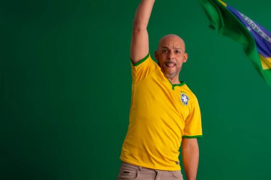 2022 kupasında Brezilya futbol takımını destekleyen Afro Brezilyalı bir adam, Brezilya bayrağı ve yüz ifadeleriyle.