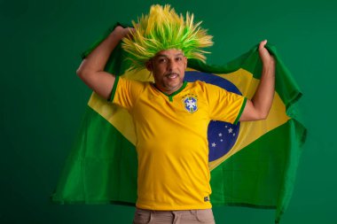 2022 kupasında Brezilya futbol takımını destekleyen Afro Brezilyalı bir adam, Brezilya bayrağı ve yüz ifadeleriyle.