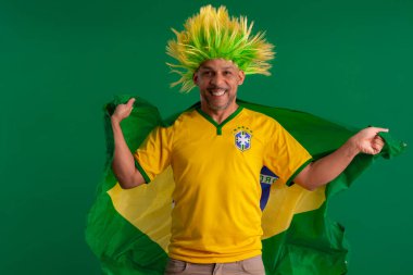 2022 kupasında Brezilya futbol takımını destekleyen Afro Brezilyalı bir adam, Brezilya bayrağı ve yüz ifadeleriyle.