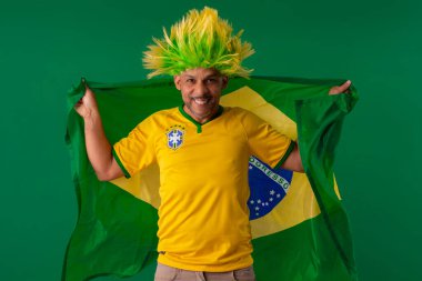 2022 kupasında Brezilya futbol takımını destekleyen Afro Brezilyalı bir adam, Brezilya bayrağı ve yüz ifadeleriyle.