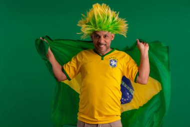 2022 kupasında Brezilya futbol takımını destekleyen Afro Brezilyalı bir adam, Brezilya bayrağı ve yüz ifadeleriyle.