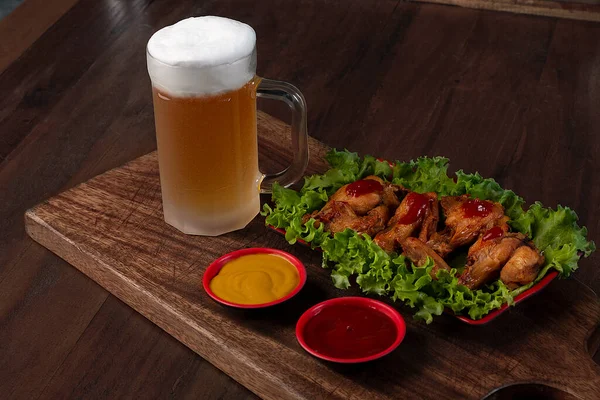 Tahtada bira bardağı ve kızarmış tavuk.