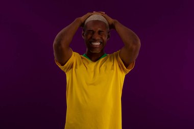 Stüdyo fotoğrafında Brezilya futbol takımı tişörtlü siyah tenli Brezilyalı adam.