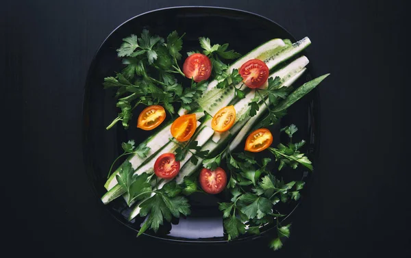 Siyah bir plaka üzerinde taze sebze salatası