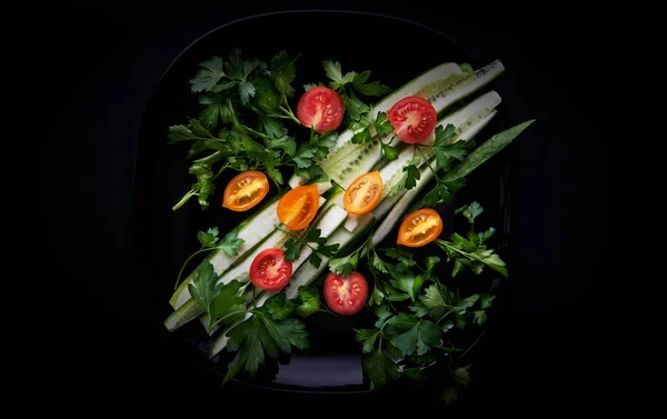 Siyah bir plaka üzerinde taze sebze salatası