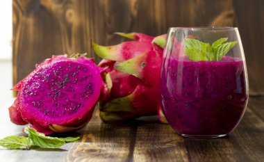 Masadaki bardağın yanında taze sıkılmış ejderha meyve suyu ve sulu meyve suyu.