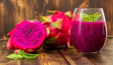 Masadaki bardağın yanında taze sıkılmış ejderha meyve suyu ve sulu meyve suyu.