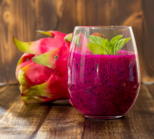 Masadaki bardağın yanında taze sıkılmış ejderha meyve suyu ve sulu meyve suyu.