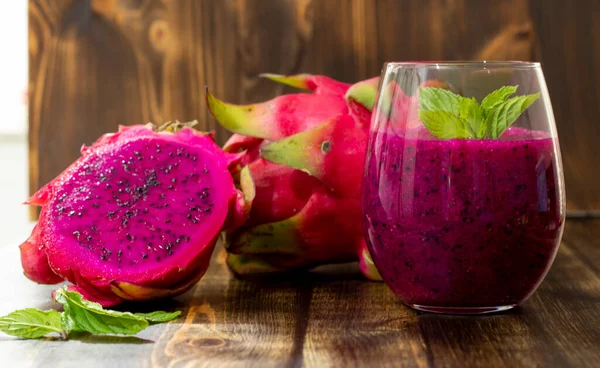 Masadaki bardağın yanında taze sıkılmış ejderha meyve suyu ve sulu meyve suyu.