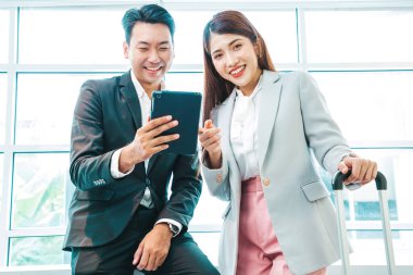 İş çifti, havaalanının kalkış alanının penceresinin yanındaki tablette bavulları ve uçuş süresini kontrol ediyor.