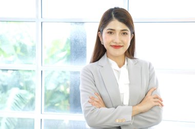 Gülümseyen Asyalı bir iş kadınının portresi. Olumlu görünümlü genç bir iş adamının portresi. Pencere arkasında çapraz poz veriyor..
