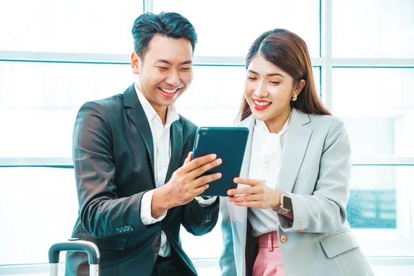 İş çifti, havaalanının kalkış alanının penceresinin yanındaki tablette bavulları ve uçuş süresini kontrol ediyor.