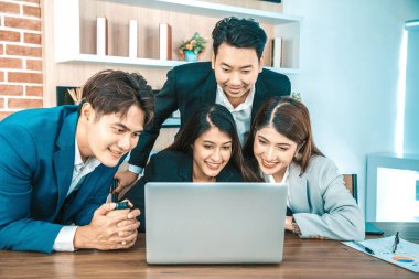 Ofisteki video konferansında genç Asyalı iş adamları ekrana bakıyor.