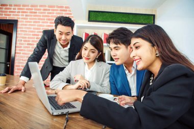 Ofisteki video konferansında genç Asyalı iş adamları ekrana bakıyor.