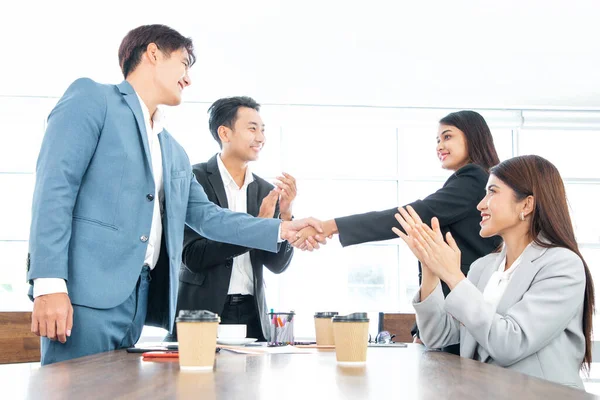 Business people shaking hands. Welcome to our team! Young modern man and women in smart casual wear shaking hands while working in the creative office