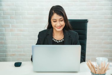 Ofisteki beyaz tuğla duvarda otururken bilgisayarla çalışan genç ve güzel iş kadınına konsantre ol..