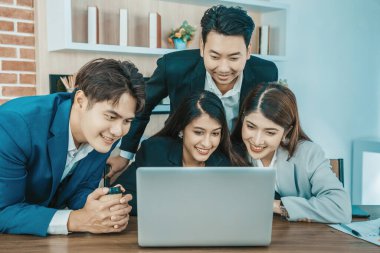 Ofisteki video konferansında genç Asyalı iş adamları ekrana bakıyor.