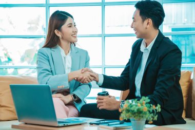 İş adamları el sıkışıyor. Takıma hoş geldin. Genç modern kadınlar ve akıllı erkekler ofiste çalışırken el sıkışırlar.