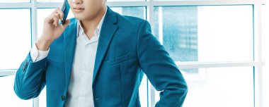 Unrecognizable  Concentrated and serious young asian businessman in office talking by mobile phone. COPY SPACE.