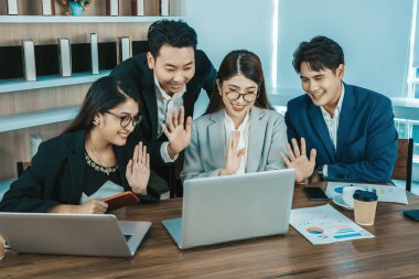 Ofisteki video konferansında genç Asyalı iş adamları ekrana bakıyor.