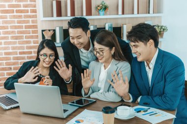 Ofisteki video konferansında genç Asyalı iş adamları ekrana bakıyor.