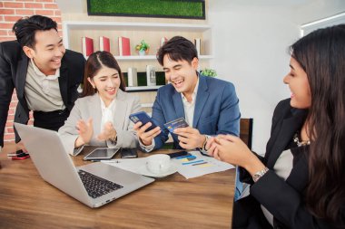 Genç Asyalı iş adamları ofiste video konferansında mobil uygulama kullanarak öğle yemeği sipariş ediyorlar.