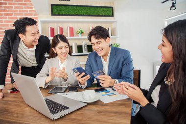 Genç Asyalı iş adamları ofiste video konferansında mobil uygulama kullanarak öğle yemeği sipariş ediyorlar.