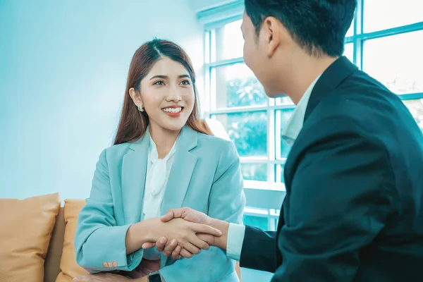 Business people shaking hands. Welcome to team. Young modern women and man in smart casual wear shaking hands while working in the office