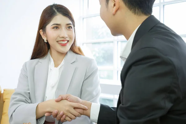 Business people shaking hands. Welcome to our team! Young modern man and women in smart casual wear shaking hands while working in the creative office