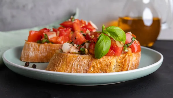 Dua potong tomat bruschetta yang terbuat dari roti ciabatta dengan tomat dadu, rempah-rempah, kemangi dan bawang putih cincang di atas piring, masakan Italia, fokus selektif — Stok Foto