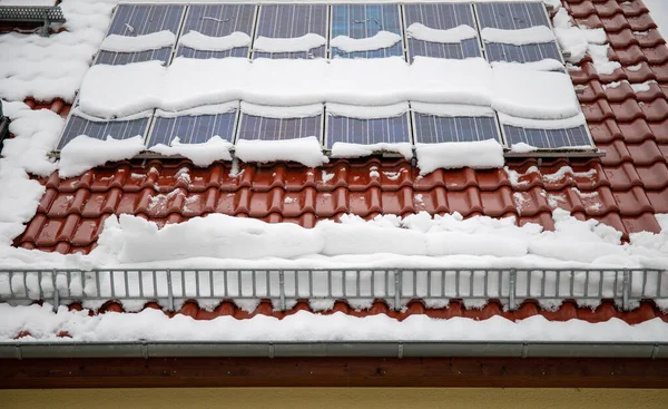 Solceller täckta med snö på vintern. Snön glider farligt ner från solcellssystemet. Snöskyddet hindrar snön från att falla fritt. — Stockfoto