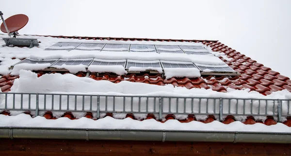 Solceller täckta med snö på vintern. Snön glider farligt ner från solcellssystemet. Snöskyddet hindrar snön från att falla fritt. — Stockfoto