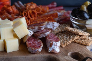 Jambonlu, salamlı, peynirli, krakerli ve zeytinli ekmek kesme tahtası. Lezzetli İtalyan kuru sosis ve peynir küplerini yakından izleyin..