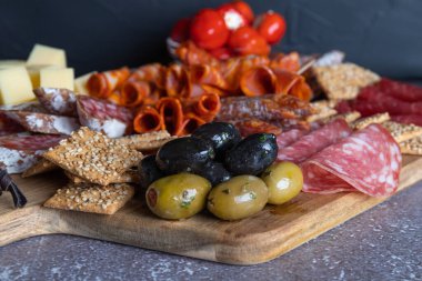 Jambonlu, salamlı, peynirli, krakerli ve zeytinli ekmek kesme tahtası. Yeşil ve siyah zeytinleri kapat.