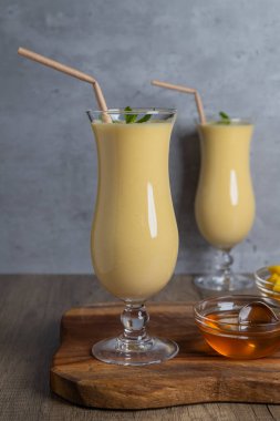 Hint kokteyli Lassi, mango, bal ve nane yaprağı iki uzun kuruyan bardakta tahta bir tahta üzerinde, fotokopi alanı, yakın plan.