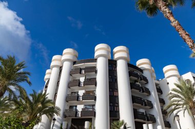 Santa Eularia des Riu, İbiza, İspanya - 16 Ekim 2021 - Binaların, palmiye ağaçlarının ve mavi gökyüzünün dış görünüşüyle gezinti alanı.