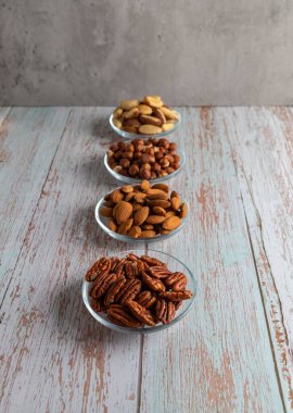 Tahta bir masada dört çeşit fındık, sağlıklı yağ ve protein yiyeceği, vegan, ketojenik diyet, bitki temelli diyet, iyi bir uyku ve rahatlama için doğal triptofan kaynakları.